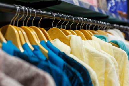 bathrobes closeup of different colors hanging on a hanger in the store, soft focus