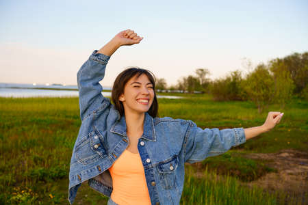 Young happy woman with long hair dancing on the beach against the sky,