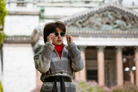 Portrait of a young woman in sunglasses in a coat against the background of St. Isaac's Cathedral