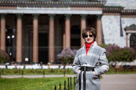 Portrait of a young woman in sunglasses in a coat against the background of St. Isaac's Cathedral