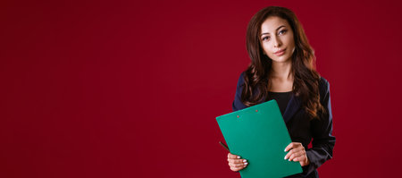 Business woman in a suit on a red background makes notes in a folder for papers