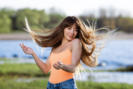 Happy young woman dancing in headphones on the shore of the bay sun sunny spring dayの写真素材