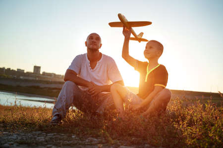 dad and son at sunset in the summer play an airplane in the sun. Family conceptの写真素材