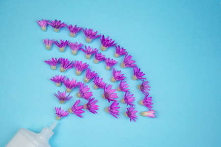 flowers fly out of a tube on a blue background, aromatherapy and cosmetology concept