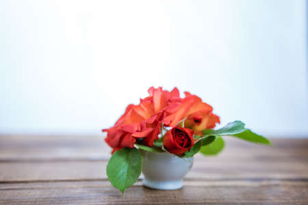 bouquet of small red roses in a vase on a wooden backgroundの写真素材