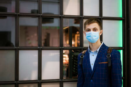 portrait of a young man in a jacket and a medical mask in a shopping mall