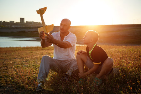 dad and son at sunset in the summer play an airplane in the sun. Family concept