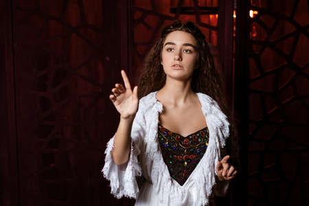 a young beautiful brunette with long loose hair in a white peignoir in the fashion of the 19th...