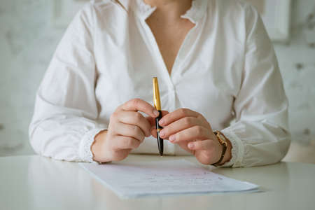 Womans hands writing on sheet with a pen. Hands of businesswoman working with documents.の写真素材