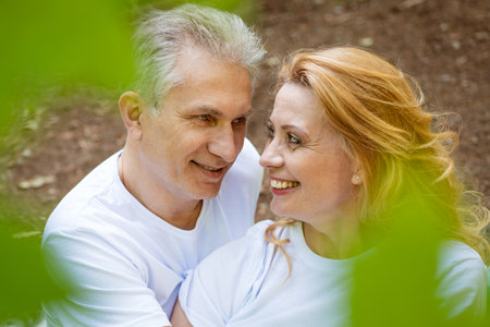 a happy elderly couple in a pair of clothes romantically spend time on a picnic in the woods on a sunny summer day.の写真素材