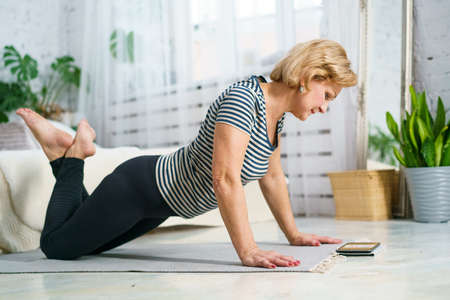 Mature woman goes in for sports looking at the monitor online, home fitness for health. The concept...