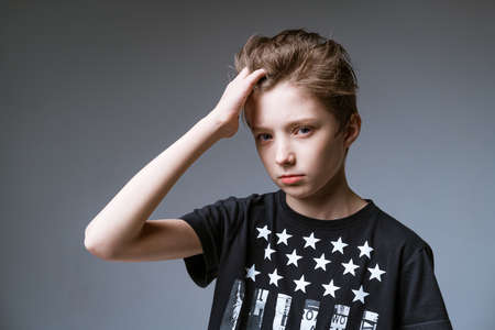 young guy of European appearance posing on a gray background in a black T-shirt, fashionable young manの写真素材
