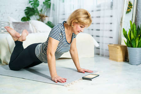Mature woman goes in for sports looking at the monitor online, home fitness for health. The concept...
