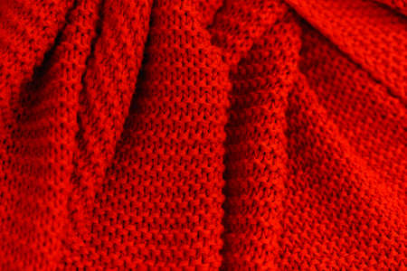 Texture of red knitted fabric close up. Wool jersey. Cozy red plaid top view. Knitted fabric close-upの写真素材
