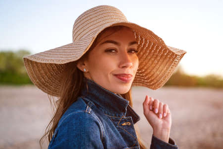 Young woman in a hat against the blue sea. Portrait of a young attractive girl in a straw hat on the...