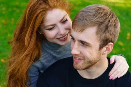 Happy young couple of Caucasian ethnicity man and woman in casual clothes sitting embracing in the...