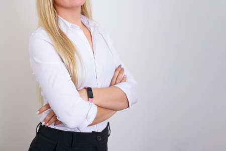 Successful business woman of Caucasian ethnicity with folded hands no face, white shirt on light...