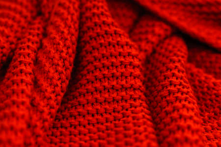Texture of red knitted fabric close up. Wool jersey. Cozy red plaid top view. Knitted fabric...