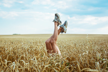 Sexy woman legs on blue sky and wheat field background. Summer vacation concept . Relaxing on a...