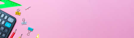 School supplies on a pink background. View from above. Copy space. Office and calculator items for...