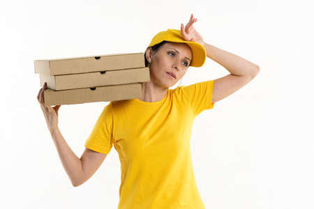 A pizza delivery woman of Caucasian appearance in a yellow uniform, holding cardboard boxes in her hands on a white background.の写真素材