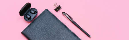 Items for business person, black glasses with notebook and pen, trendy wireless headphones on pink background. With place for signatureの写真素材