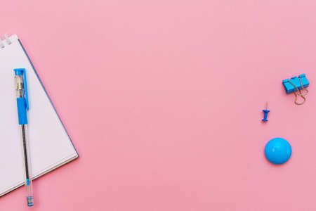 Open spiral notepad on pink background, notepad and blue pen lie on paper, flat lay concept