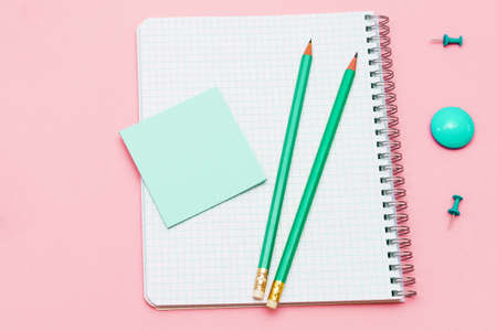 Blank spiral notepad with white page and wooden pencil on pink background. Workplace with a notepad and a sticker on a colored background. Album for entering text, top view.の写真素材