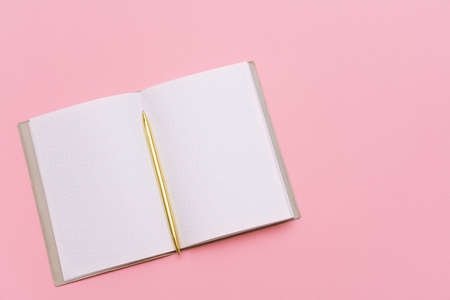 Notepad and gold pen on a pink background. Mock up, top view, copy space. Colored blocks concept.の写真素材