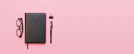 Black glasses, notebook and pen. Subjects for training and business on a pink background. Back to...