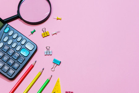 Various office supplies on a pink background. Back to school concept. View from above. Calculator...