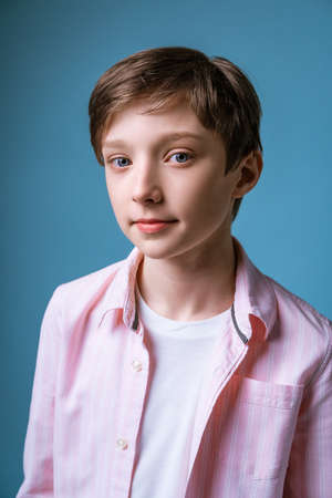 Portrait of a young guy of European appearance in a white T-shirt and a pink shirt posing on a blue backgroundの写真素材