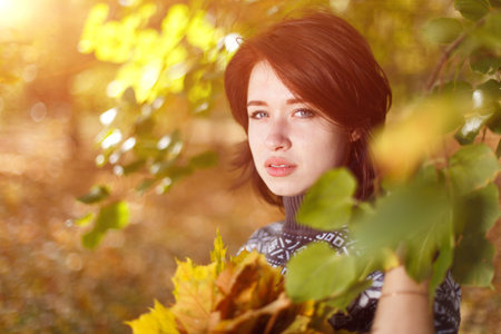 Outdoor portrait of young caucasian woman in knitted sweater posing against nature background. A...