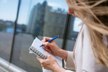 Overworked business woman. Multitasking business woman talking on a mobile phone in a light jacket near an office building. Caucasian womanの写真素材