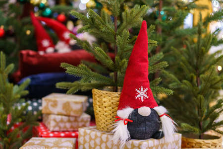 Santa toy on the background of a christmas tree with gifts. Christmas mood. Handmade item for decoration for the new yearの写真素材