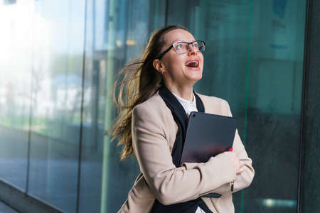 A successful business woman of Caucasian ethnicity with a folder of papers in her hand, in a coat...