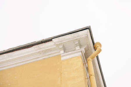 Bottom up view of the sky and rooftops of the old city. Roof corner and downspout on gray sky backgroundの写真素材