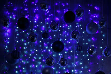 Christmas balls and garland glow as a festive atmospheric blue background. Beautiful card with bokeh