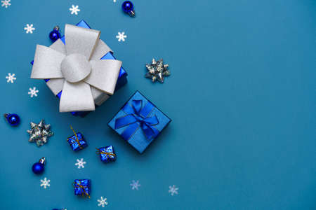 Winter background blue. Cute gift box with blue ribbon, christmas balls in a christmas composition...