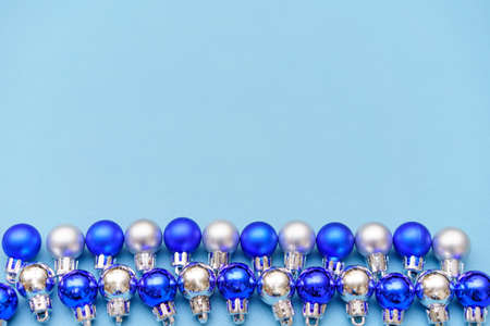 New years composition. Christmas balls of blue and silver color lie in a row on a blue background. Flat lay, top view, copy spaceの写真素材