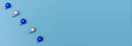 Blue and silver christmas decoration balls baubles on blue background with copy space. New year card. Minimalistic style. Flat lay.の写真素材