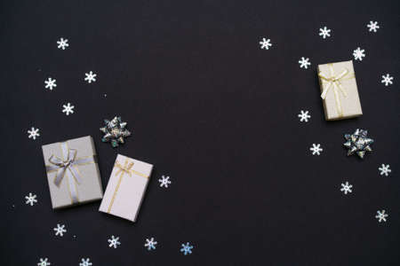 Christmas background from gift boxes of silver color, decorative snowflakes on dark black background. Festive christmas background. Banner layout, postcard. Flat lay. Copy space.の写真素材