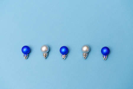 New years composition. Christmas balls of blue and silver color lie in a row on a blue background. Flat lay, top view, copy spaceの写真素材