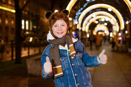 Caucasian school-age boy on a christmas walk around the city, evening december holiday new year,...