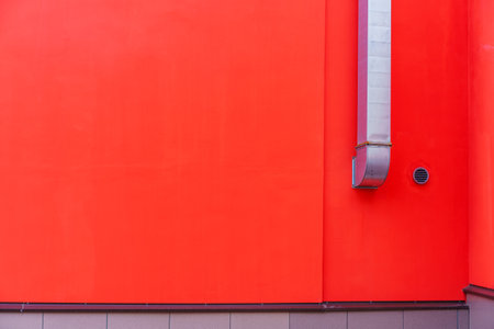 Painted red wall of the house with a hood from a galvanized box. Vintillation solution in...