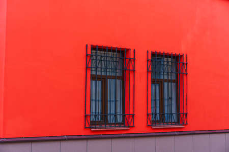 Red facade of the building with wooden windows on which there are iron bars for protection.の写真素材
