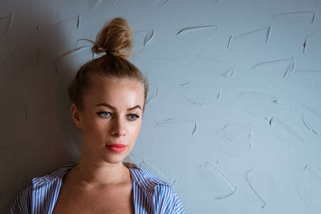 Portrait of a woman with a tail on her head against the background of a gray wallの写真素材