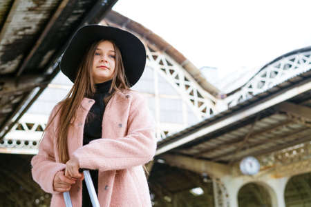 Young woman with suitcase on platform of station. Traveler girl waiting for train enjoying a weekend...