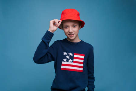 Waist shot happy and contented handsome young man wearing red panama hat and blue us flag sweater...
