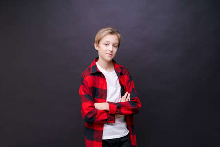 Close-up headshot of confident concentrated young man in plaid shirt looking at camera studio portrait isolated on black studio background. Thoughtful millennial guy poses for a photo album.の写真素材